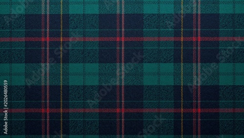 Close-up of traditional tartan fabric with detailed plaid pattern in shades of green and blue