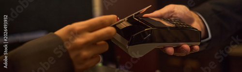 Schilderij op canvas Close up of customer hand tapping payment card on terminal, processing contactless transaction in retail checkout
