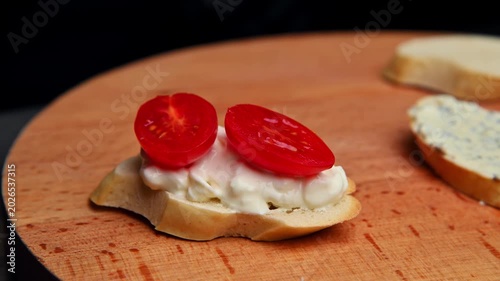 Preparing bruschetta with sliced tomatoes on toasted bread in kitchen setting