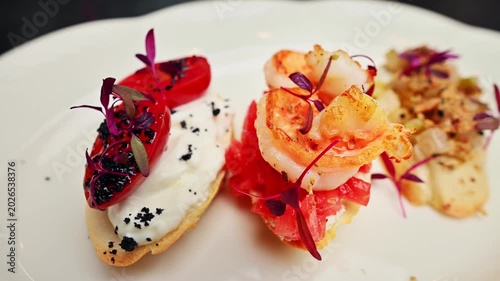 Bruschetta with shrimp, tomatoes, and herbs on a white plate, close-up view
