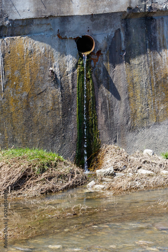 Fototapeta premium Leaking pipe releases water into muddy ground