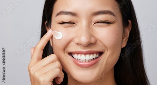 Woman applying cream to her face with a smile on her face