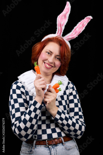 Smiling woman in bunny ears costume holding carrots playfully posing