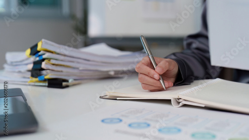 Bilde på lerret Asian woman writing in notebook at office desk for business finance paperwork