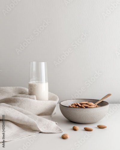 Minimal almond milk glass and bowl with spoon on linen cloth plant based snack concept for banner background and packaging mockup