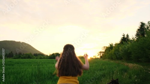 Preteen girl raising hands over warm sunset, enjoying life and nature. Child on summer field enjoying sunlight. Silhouette of preteen kid in sunlight rays. Air, environment concept. Dream of flying