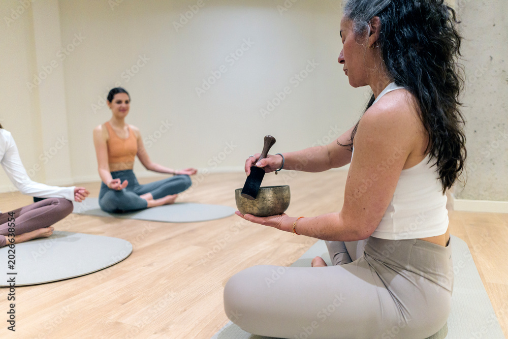Fototapeta premium Group of women meditating with singing bowl for sound healing