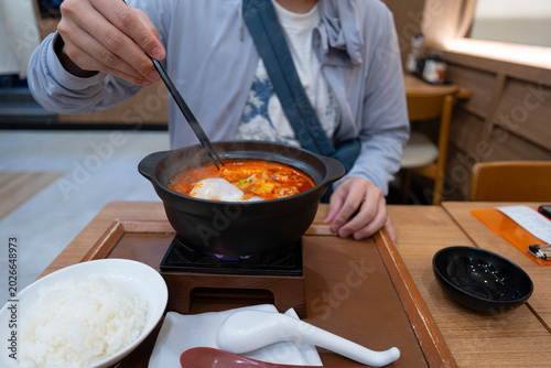 Tableau sur toile Crop anonymous man with chopsticks eating yummy Kimchi Soup in hot bowl at Japanese restaurant