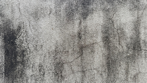 Bild auf Leinwand An aged concrete wall surface with dark stains and visible cracks, reflecting weathering and deterioration over time