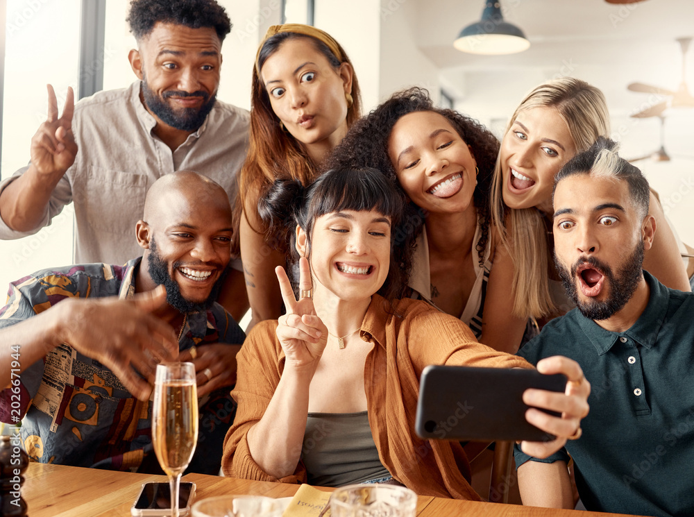 Obraz premium Selfie, funny face or friends in restaurant with celebration, reunion or bonding in digital memory. Happy, tongue out or people with peace sign, birthday party or group gathering for social media.