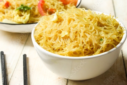 Bild auf Leinwand a bowl of stir-fried vermicelli on a wooden table