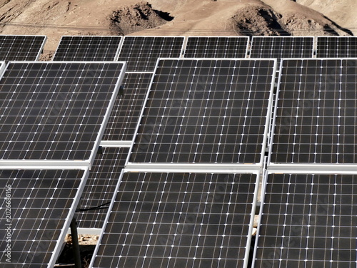 Solar farm in the desert : many solar panels in open space in arid environnement, renewable energy concept
