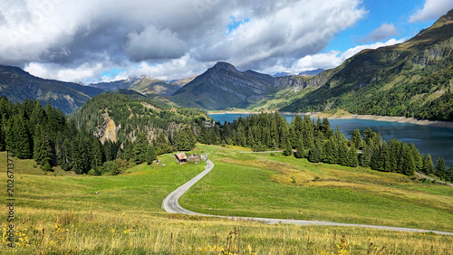 Obraz na płótnie Alpine landscape showing Roselend Lake with road and mountains, Beaufort, Savoie, France, Europe