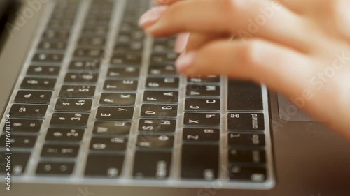 Hands typing on a silver laptop keyboard at a desk during daytime