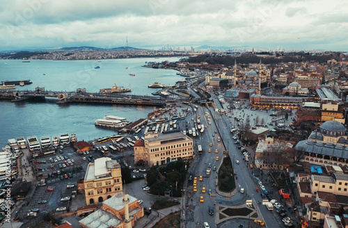 Galata Bridge connects both sides of Istanbul as traffic flows steadily and natural coastal activity surrounds the scene.