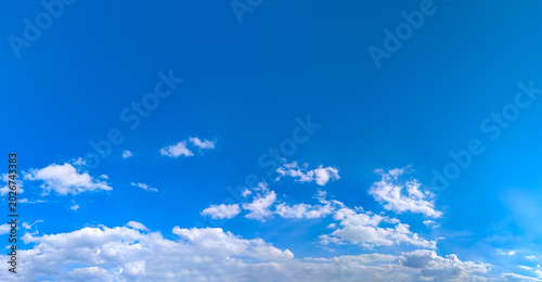A feathery fanning of cumulus clouds in a serene, empty blue sky atmosphere. Panorama with big copy space for text viewed from below. Meteorological celestial spectacle. Blue skies in the turmoil.