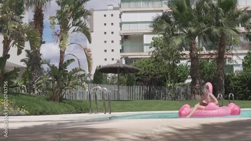 Little girl swimming in the pool of her house on an inflatable pink flamingo