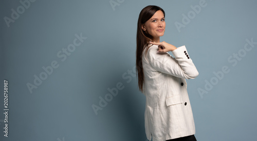 Happy professional business woman looking at camera pointing finger away at copy space, isolated at blue background