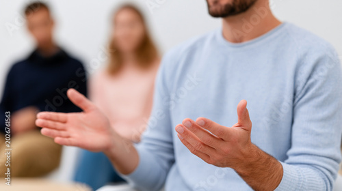 Unrecognizable man speaking calmly with open hand gestures during meeting. Concept of emotional intelligence and persuasive communication skills.
