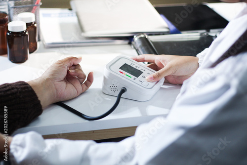 Fotografija A doctor's hands carefully taking a patient's blood pressure using a sphygmomanometer