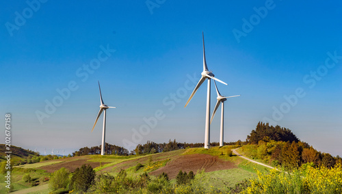 Fotografía wind turbines  on hill under blue sky in greenery meadow in vaucluse french coun