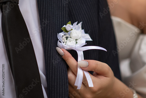 Photos bride adjusts the groom's boutonniere before the wedding