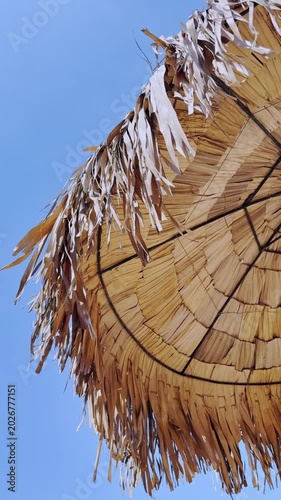 Straw beach umbrella under a clear blue sky