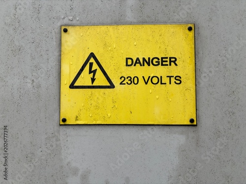 Danger 230 Volts electrical hazard warning sign on a weathered concrete wall.