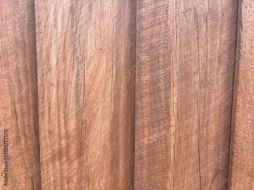 Close-up view of a rustic, weathered wooden fence with vertical planks displaying natural grain patterns and warm tones.
