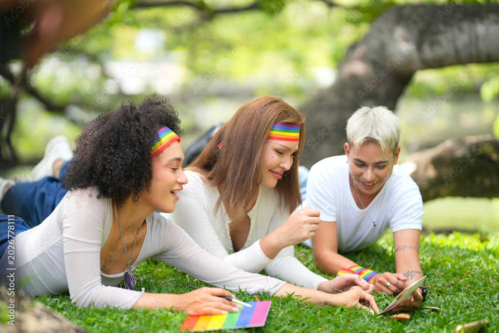 Fototapeta premium Diverse friends in park wearing rainbow headbands, celebrating pride month together
