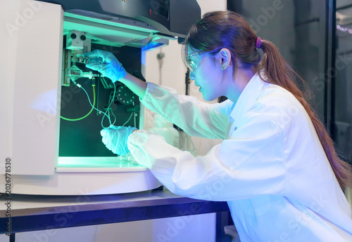 Scientist in lab coat and gloves working with advanced analytical equipment