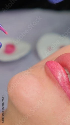 Permanent makeup artist tattooing lips with pink pigment for a perfect, long-lasting contour