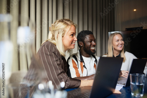 Smiling male entrepreneur sitting with female colleagues in meeting at office