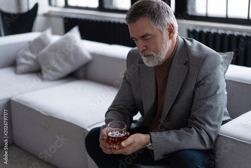 Confident mature businessman chilling relaxing drinking enjoying whiskey after work.