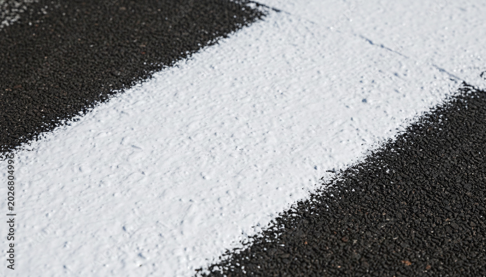 Fototapeta premium Ultra white reflective cooling paint texture over rough dark asphalt