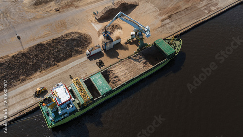 High angle view of machine unloading sand from ship at harbor