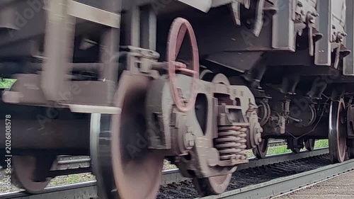 close-up view wheels moving freight train, with steel carriages passing quickly along railway tracks. motion blur emphasizes concept speed and transport.