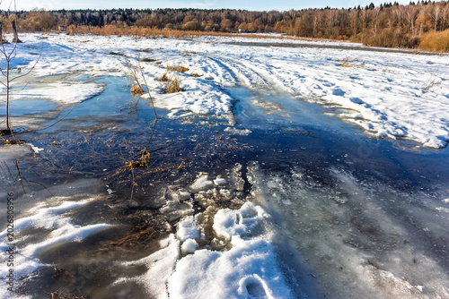 Фотография Muddy flooded track on a melting snow field during early spring thaw with slushy