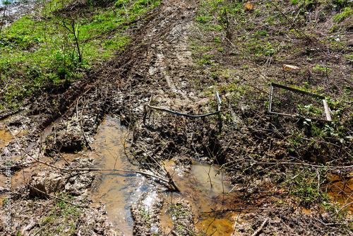 Tablou pe pânză Rusty metal barriers block a muddy forest path to stop off-road motorcycles, sho