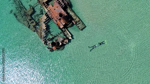 Aerial view of the famous Epanomi shipwreck submerged in crystal clear turquoise waters near the sandy beach spit in Halkidiki, Greece.