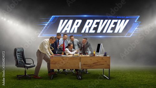 Quadro su tela Business fans watching soccer decision with var review text on stadium field