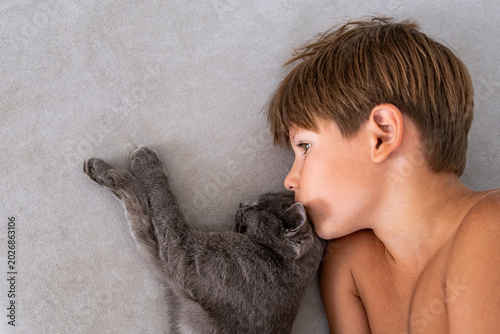 Foto Tender Moment Between a Child and a Gray Cat, Close-Up of Affection A delightful image of a smiling boy and a gray cat gazing into each other’s eyes, capturing a playful and heartwarming moment