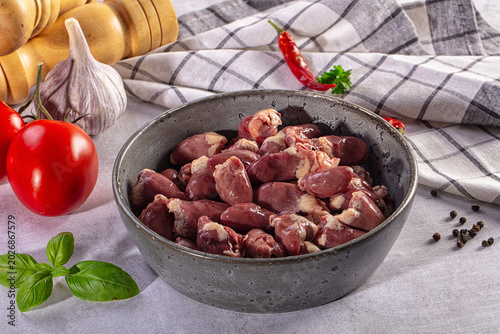 Valokuva Raw chicken hearts in a bowl with fresh vegetables, herbs and spices for cooking