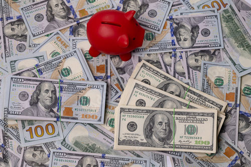 Obraz na plátně High angle view of red piggy bank on large amount of one hundred dollar banknotes