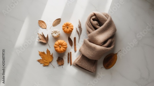Cozy autumnal scarf wrapped around with pumpkins leaves cinnamon sticks and dried flowers on neutral surface