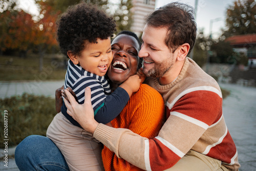 Photos Happy multi-ethnic family parents and child hugging outdoors