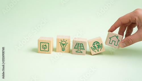 Sustainability concept showing hand placing wood block with house icon.