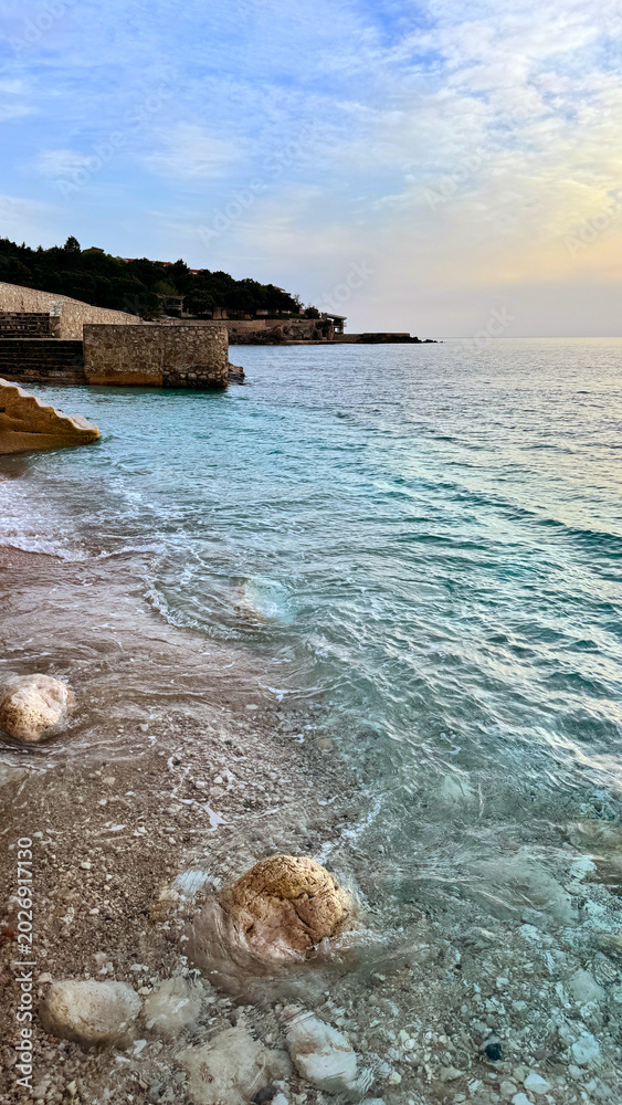Fototapeta premium Dobra Voda shoreline with turquoise Adriatic water and stone quay at sunrise