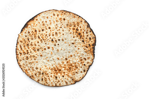 One traditional hand-made round shmurah matzah for Passover holiday on white background with copy space. Top view, flat lay