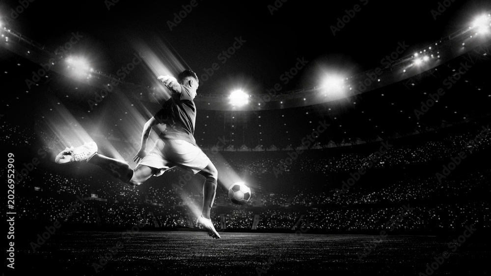 Naklejka premium Soccer player jumping for powerful kick in black and white stadium light. Concept of decisive attack, dramatic match moment, sport campaign and cinematic football energy.